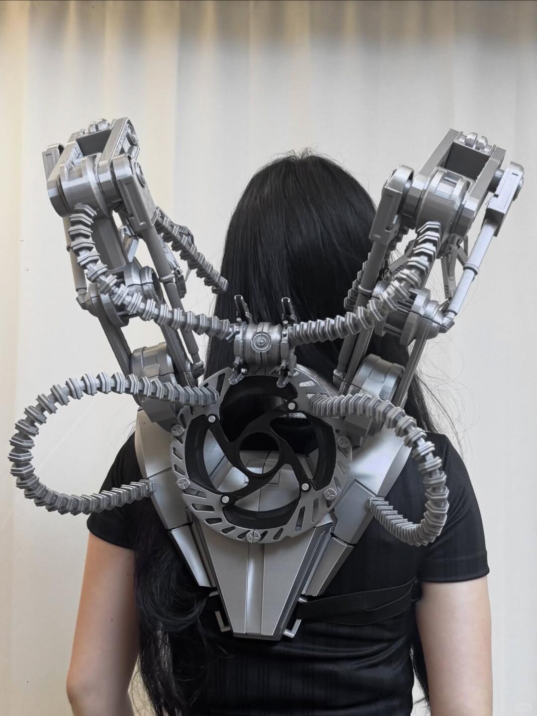 Silver articulated mechanical rig extending from the wearer's back.