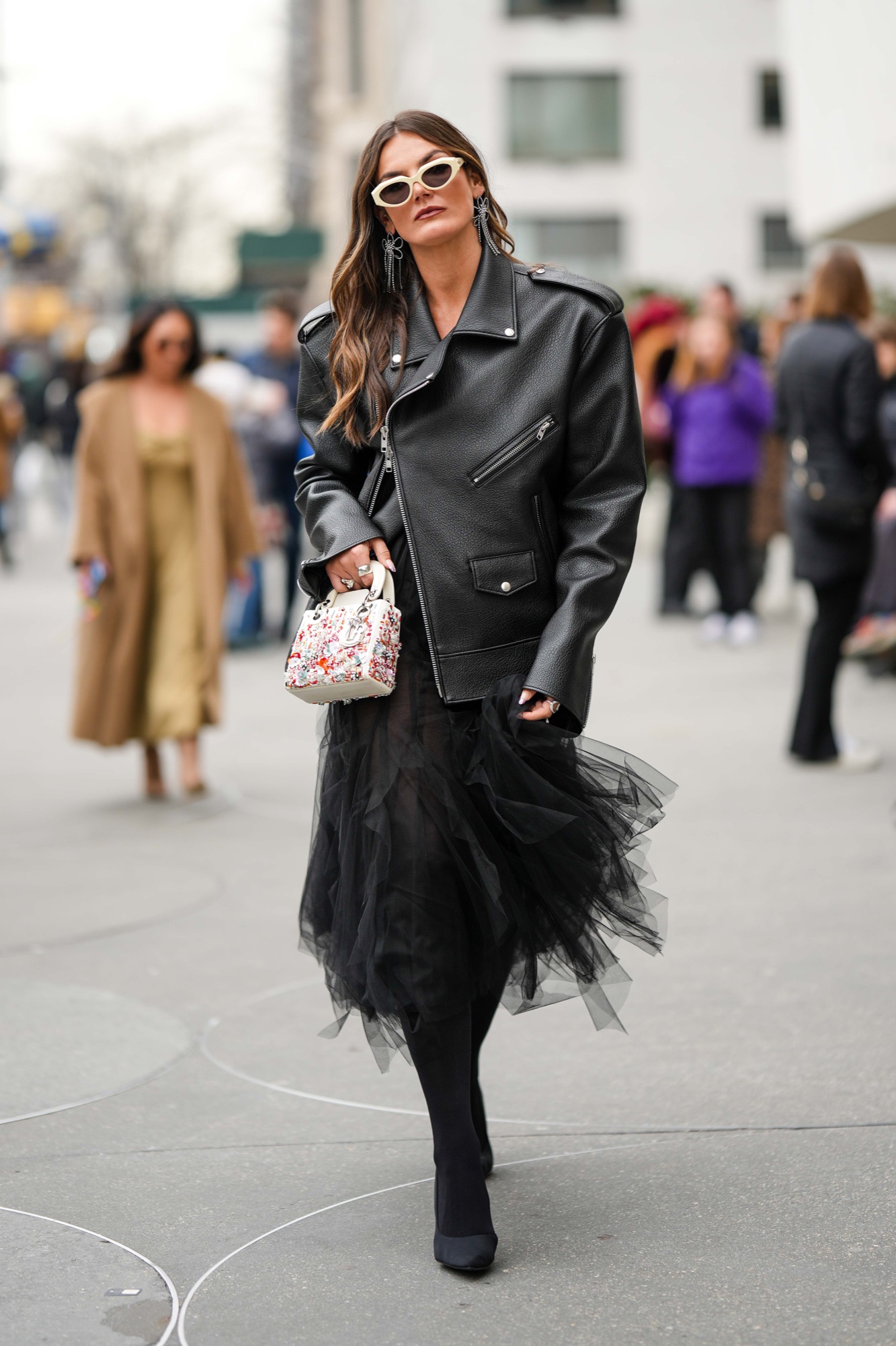 Oversized structured black leather jacket worn over a voluminous black tulle skirt.
