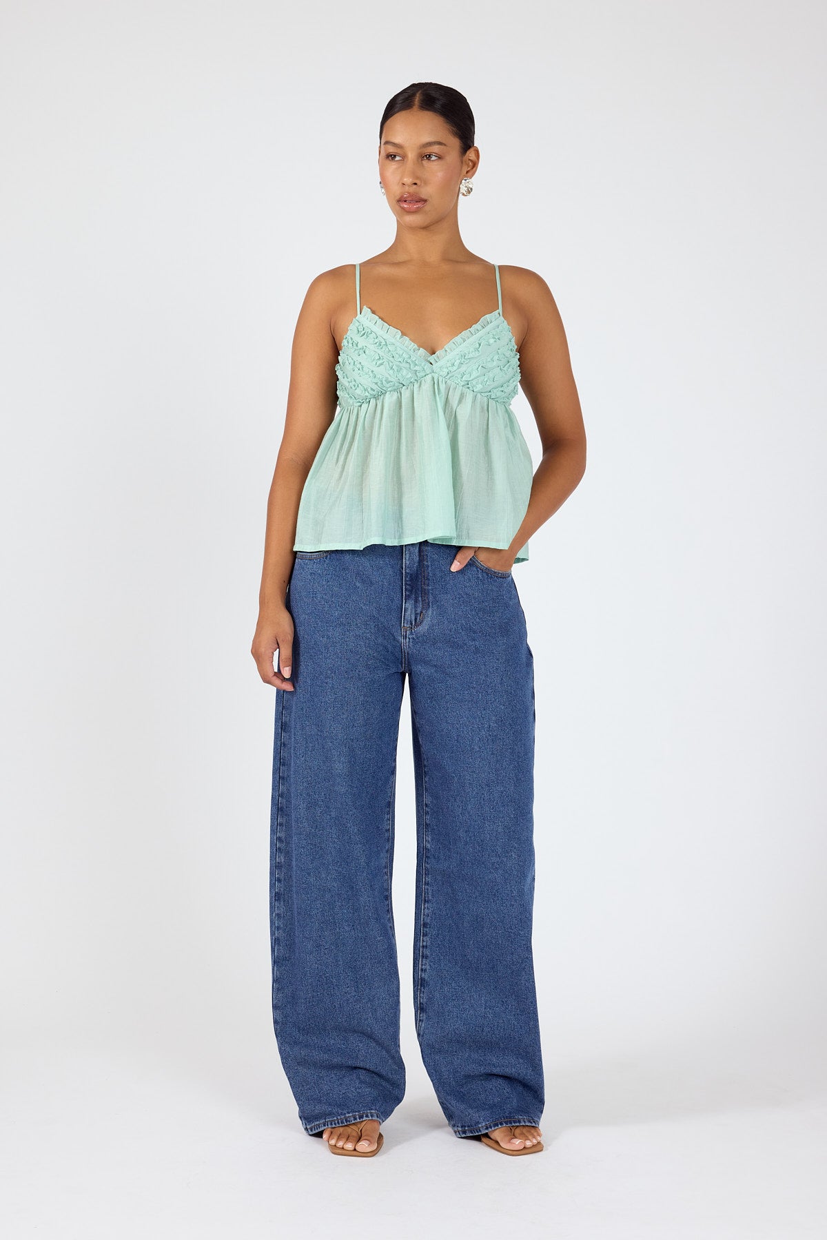 Mint green camisole styled with wide-leg blue denim jeans.