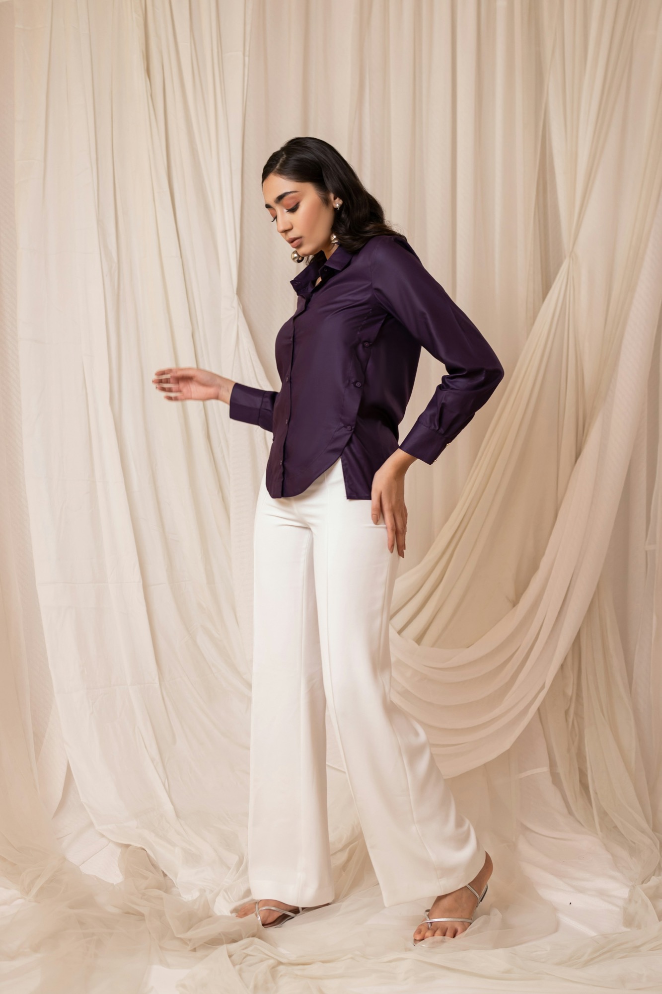 Deep purple satin shirt paired with flowing white trousers.