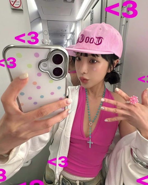 Accessory styling with a pink cap, necklace, bracelets, and color accents.